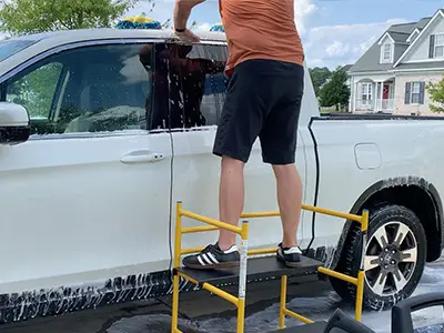 Using portable scaffolding to wash a vehicle